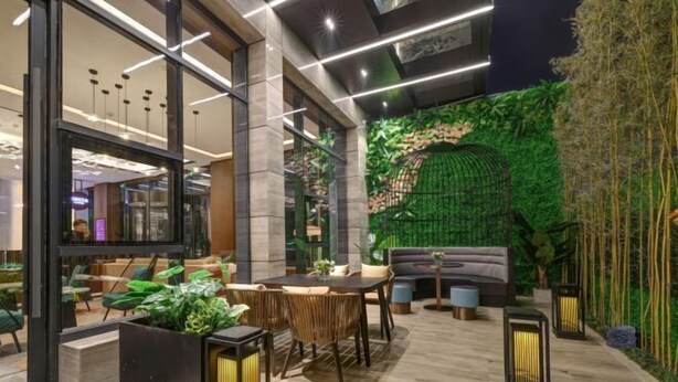 A modern indoor space with a dining area, seating, and a green wall with plants. - Jinjiang Metropolo Hotel (Yancheng Dafeng Changxin Road) (Yancheng)