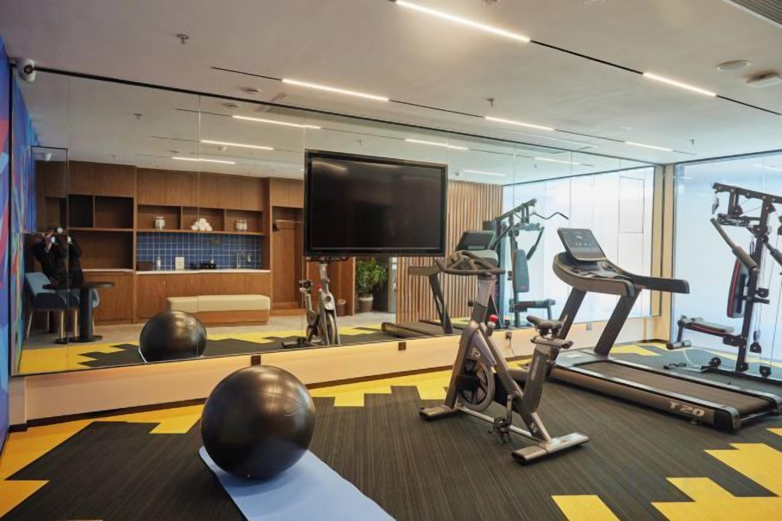 A gym with exercise equipment, a TV, and a seating area with a view of the room.