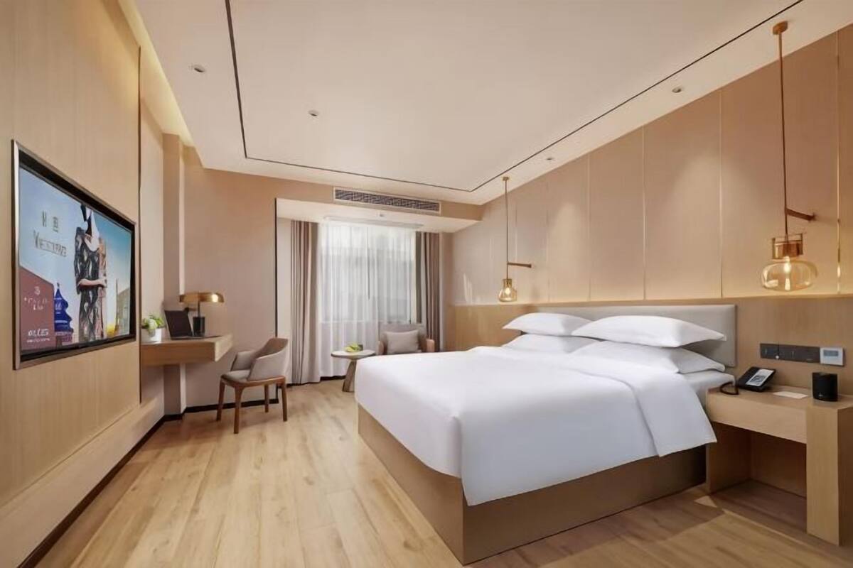Una habitación de hotel moderna con una cama grande, un escritorio, una silla y un televisor.