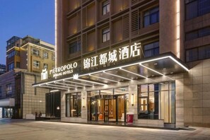 A hotel entrance with a modern design, featuring a prominent sign and a covered entrance area.