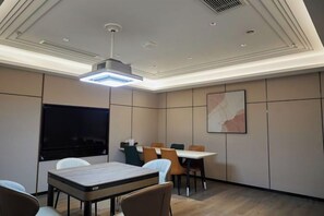 Ett konferensrum med en stor skärm, bord, stolar och en modern takdesign.