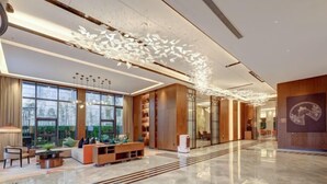 A spacious lobby with a modern design, featuring a large seating area, a decorative ceiling installation, and large windows providing natural light. - Jinjiang Metropolo Hotel (Yancheng Dafeng Changxin Road) (Yancheng)