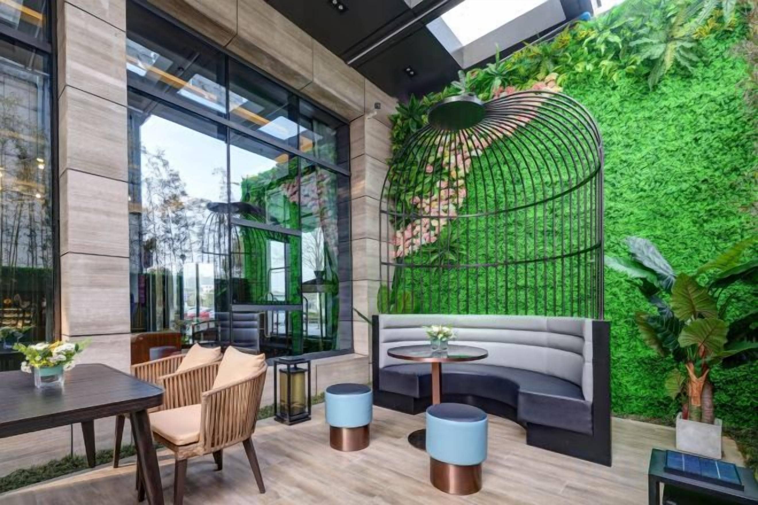 Un intérieur moderne avec un coin salon, une grande fenêtre et un mur végétal.