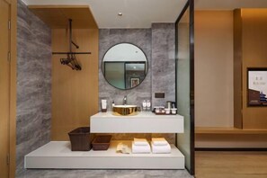 A modern bathroom with a marble wall, a round mirror, a gold sink, and neatly arranged toiletries. - Jinjiang Metropolo Hotel (Yancheng Dafeng Changxin Road) (Yancheng)