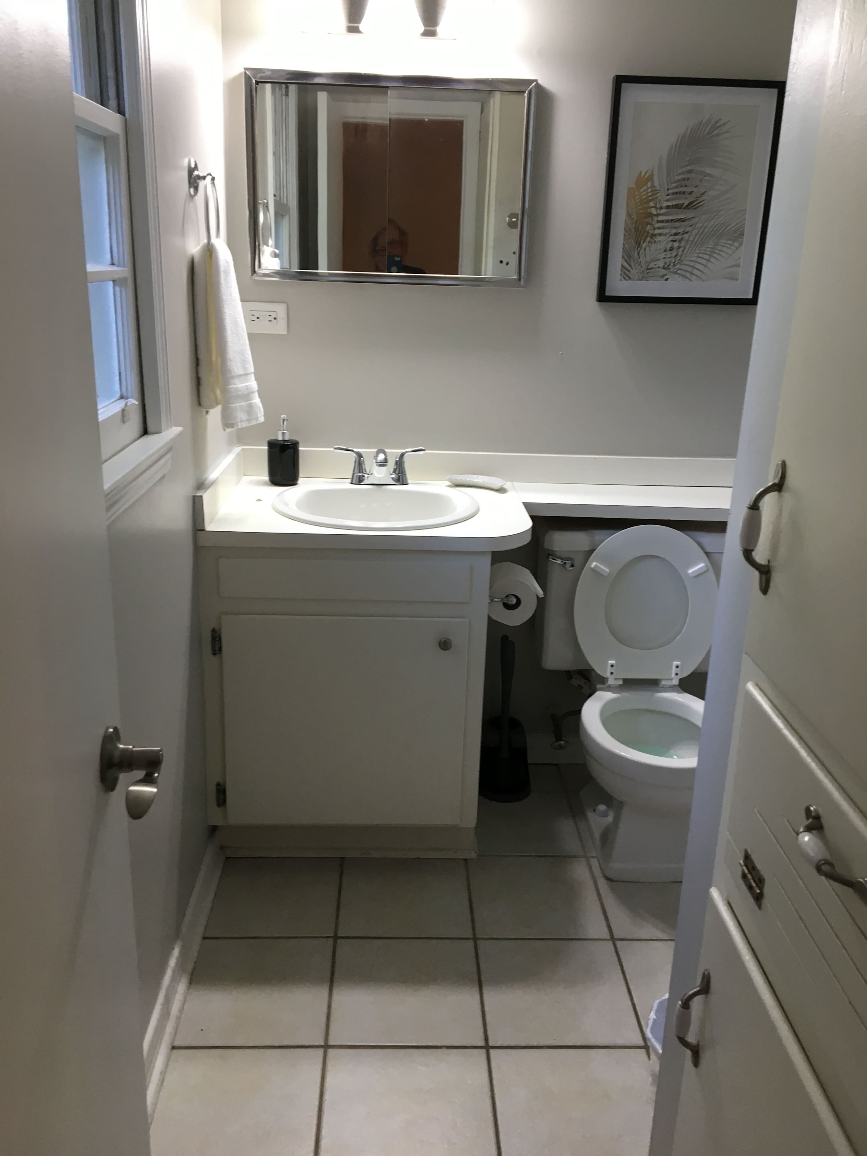 A compact bathroom with a white sink, mirror, and toilet.