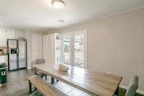 A kitchen with a wooden table, a bench, and a view through glass doors.