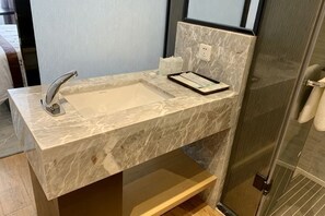 Une salle de bain avec un lavabo en marbre, un miroir et un espace douche.