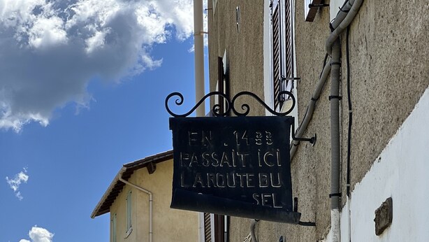 A narrow street with buildings, a sign reading "EN 1438 PASSAIT ICL LAROUTE DU SEL," and a car parked on the side. - Nice little studio in the Vésubie valley, Mercantour Park (Roquebillière)