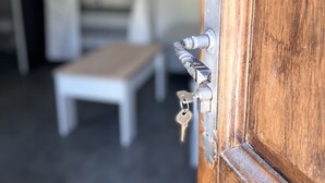 A wooden door with a metal handle and keys, a white bench, and a white curtain in the background. - Nice little studio in the Vésubie valley, Mercantour Park (Roquebillière)