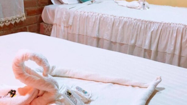 A hotel room with two beds, each with a white bedspread and pillows. There is a towel on the floor and a small decorative item on one of the beds. - Hotel Flor del Campo (Pedro Vicente Maldonado)