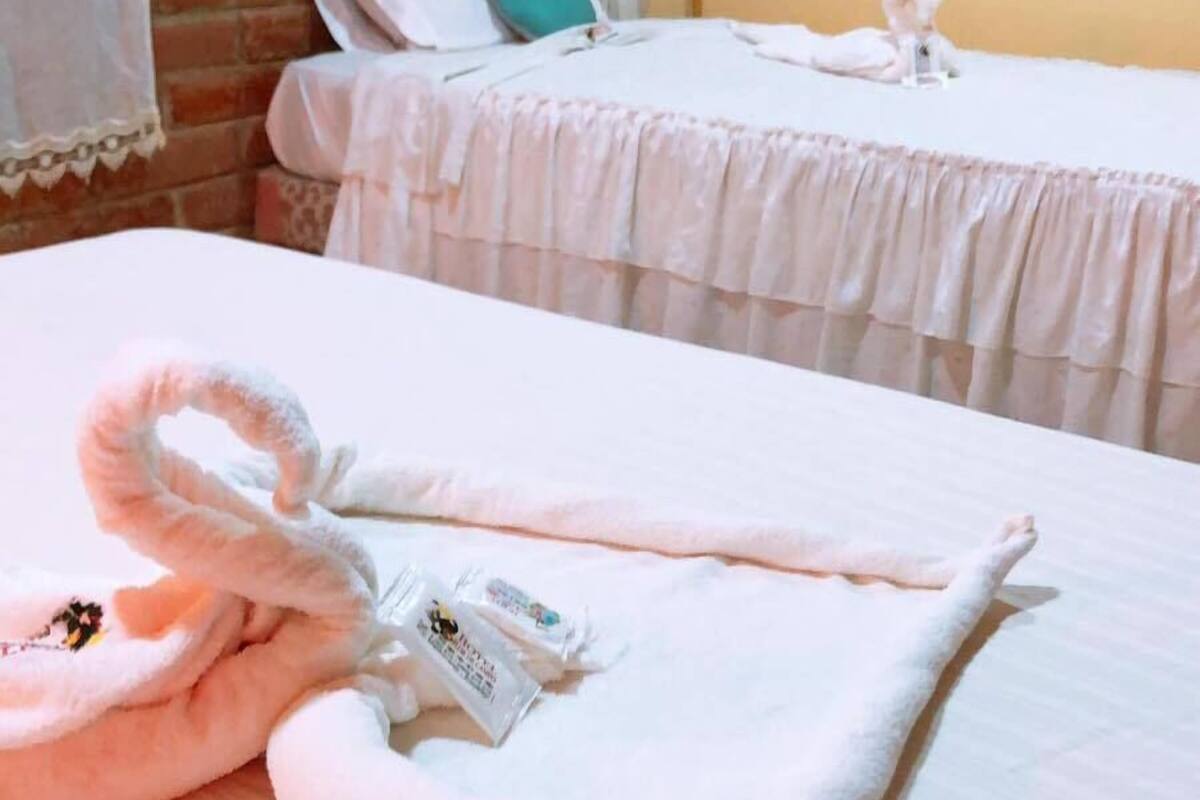 A hotel room with two beds, each with a white bedspread and pillows.