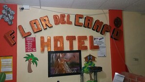 A wall with a sign reading "FLOR DEL CANPO HOTEL" and emergency contact numbers. - Hotel Flor del Campo (Pedro Vicente Maldonado)