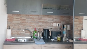 A modern kitchen with grey cabinets, a tiled backsplash, and a stainless steel sink. There are plants on the countertop and a coffee machine. - Quiet oasis of well-being for 2-5 persons, 300 m to the beach (Nea Mesangala)