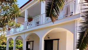 A two-story building with a covered patio area, a balcony, and a well-maintained lawn. - Quiet oasis of well-being for 2-5 persons, 300 m to the beach (Nea Mesangala)