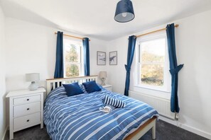 A bedroom with a bed, two bedside tables, a window with curtains, and a ceiling light. - Spacious Cottage, Parking nr Saunton Sands (Braunton)