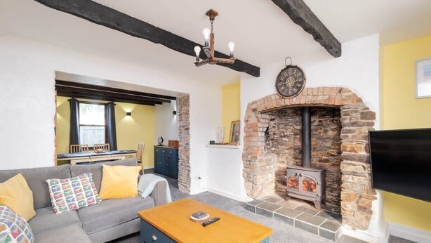 Ein Wohnzimmer mit Kamin aus Stein, einer Couch, einem Couchtisch und einem Fernseher.