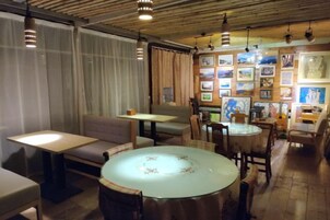 Una habitación con una mesa redonda, un sofá y una mesa de comedor. Hay sillas alrededor de las mesas. El suelo es de madera y el techo tiene vigas de madera.