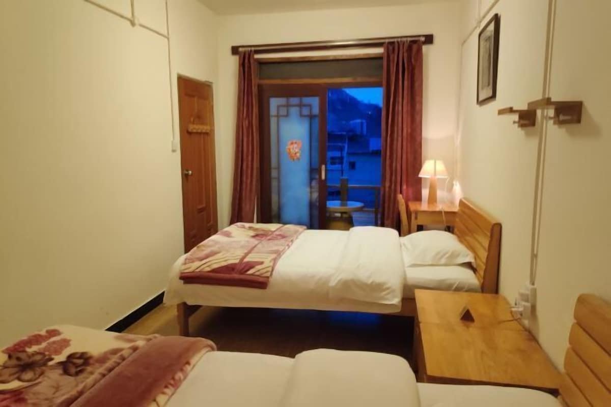 Une chambre d’hôtel avec deux lits, une table de chevet en bois et une petite table.