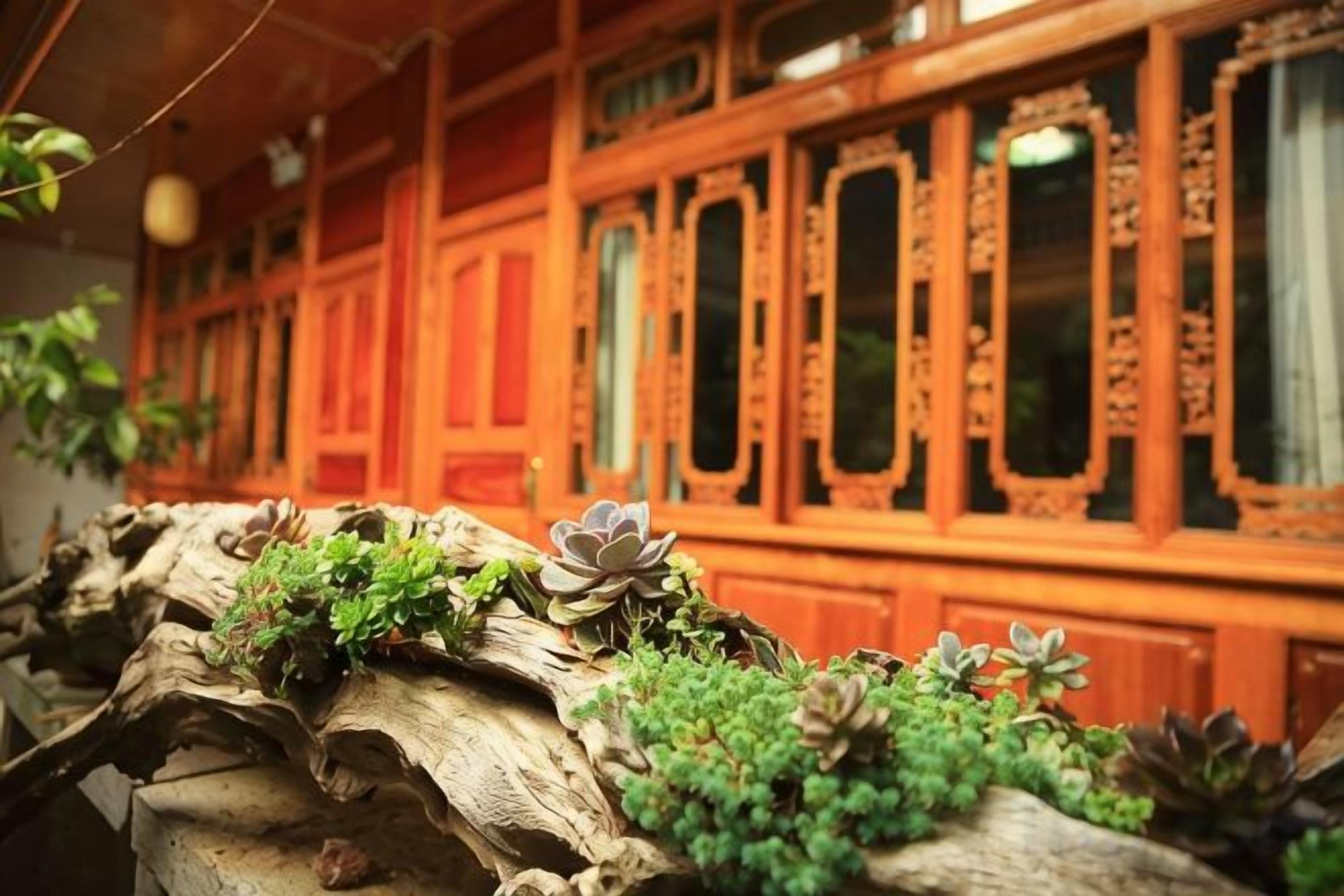 A traditional wooden building with ornate windows and a wooden structure with plants.