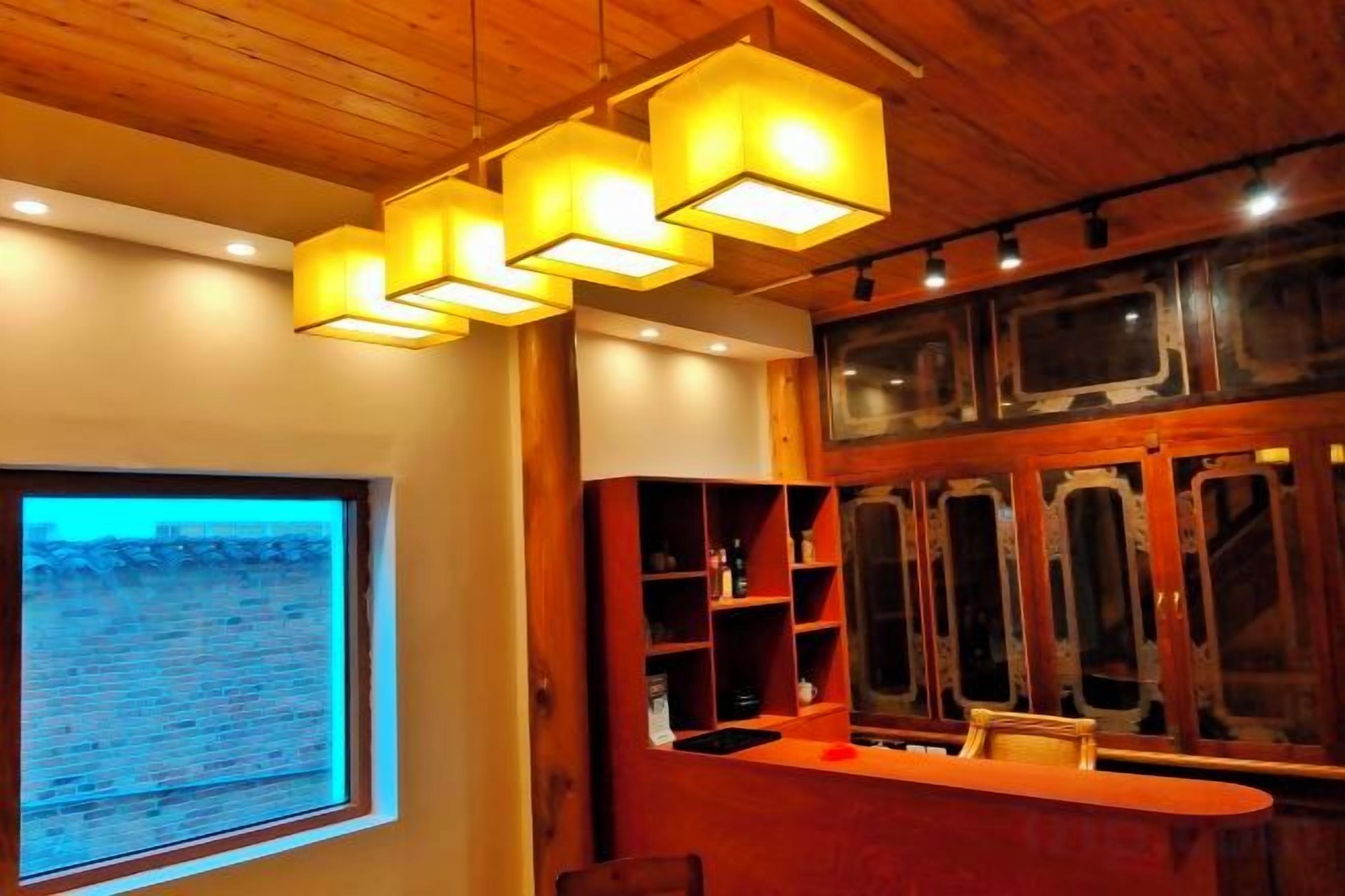 Zona de bar con techo de madera y luces colgantes, un ventanal con vistas al desierto y estantes con botellas.
