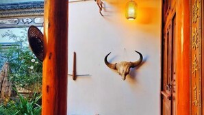 Un interior tradicional con un cráneo de toro montado en la pared, un farol colgante y una puerta de madera con inscripciones doradas.