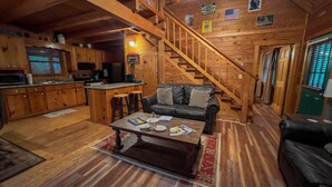 A cozy cabin interior with a kitchen, dining area, and a staircase. - Labor Day at Pike's Peak - Wifi and Hot Tub! - Callaway Gardens (Warm Springs)