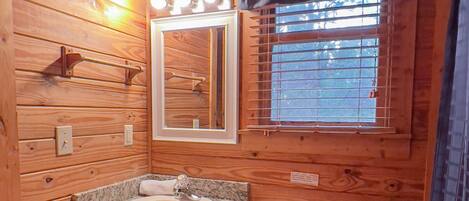 Ein Badezimmer einer Holzhütte mit Waschbecken, Spiegel und Toilette.