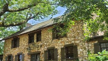 A stone building with multiple windows and a tree in front.