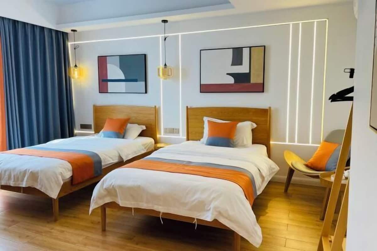 A hotel room with two beds, a chair, and artwork on the walls.