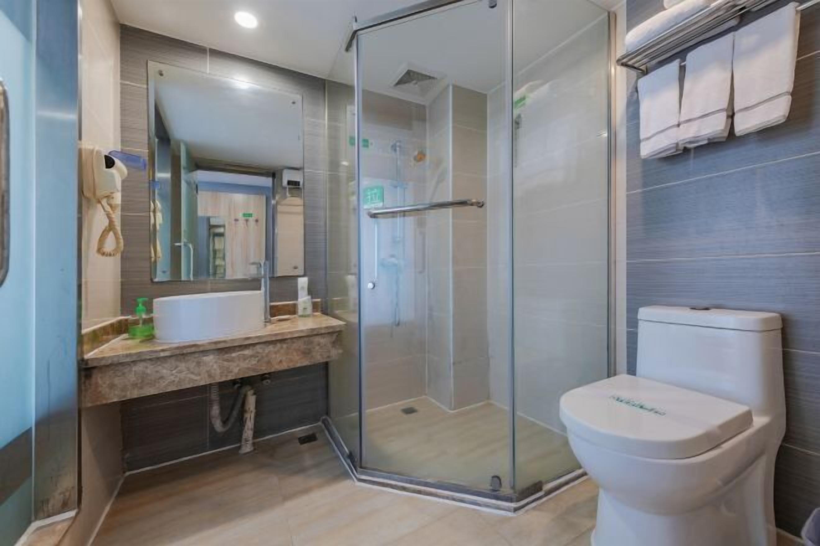 A modern bathroom with a glass-enclosed shower, a white sink, and a toilet.