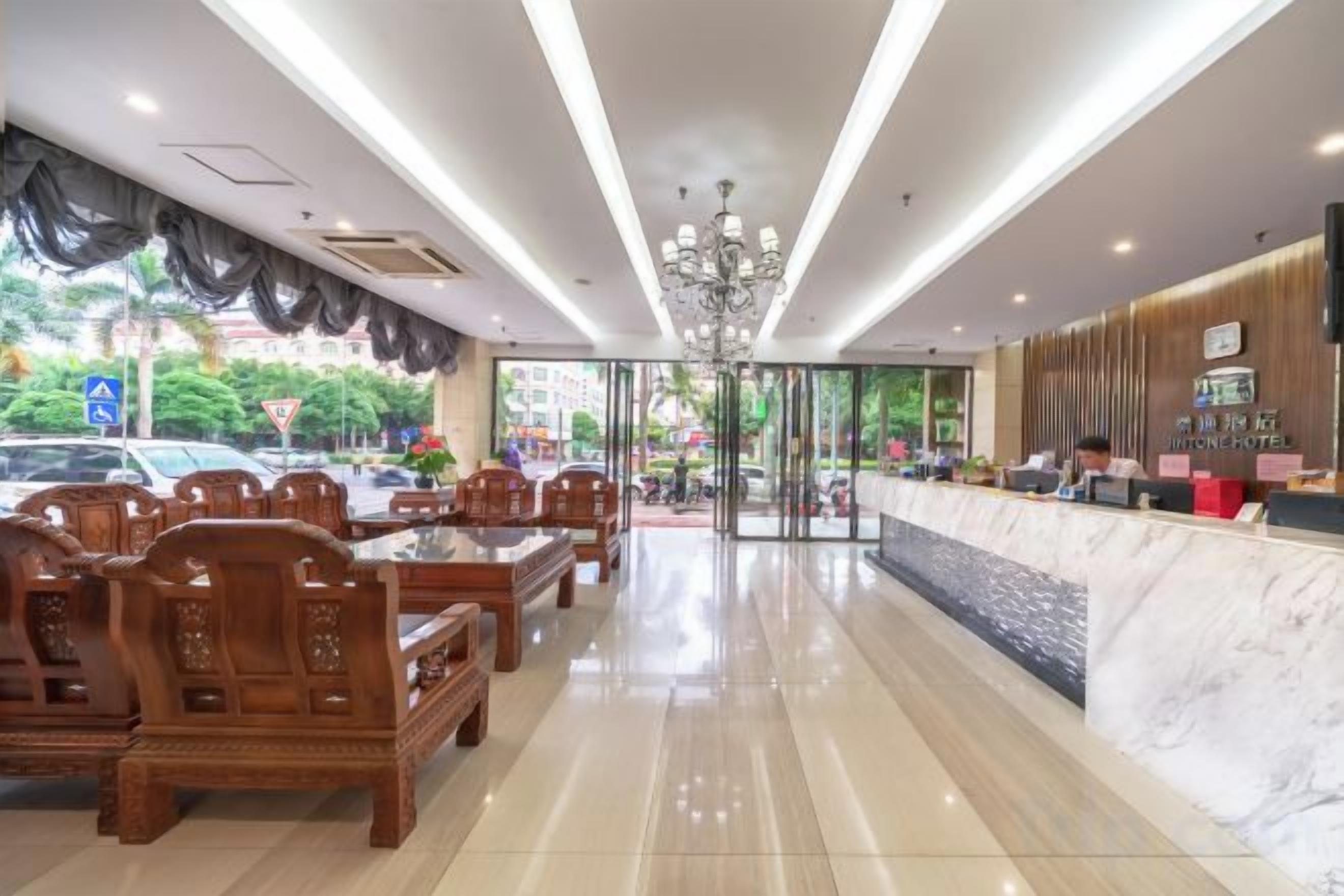 A hotel lobby with a reception desk, seating area, and a chandelier.