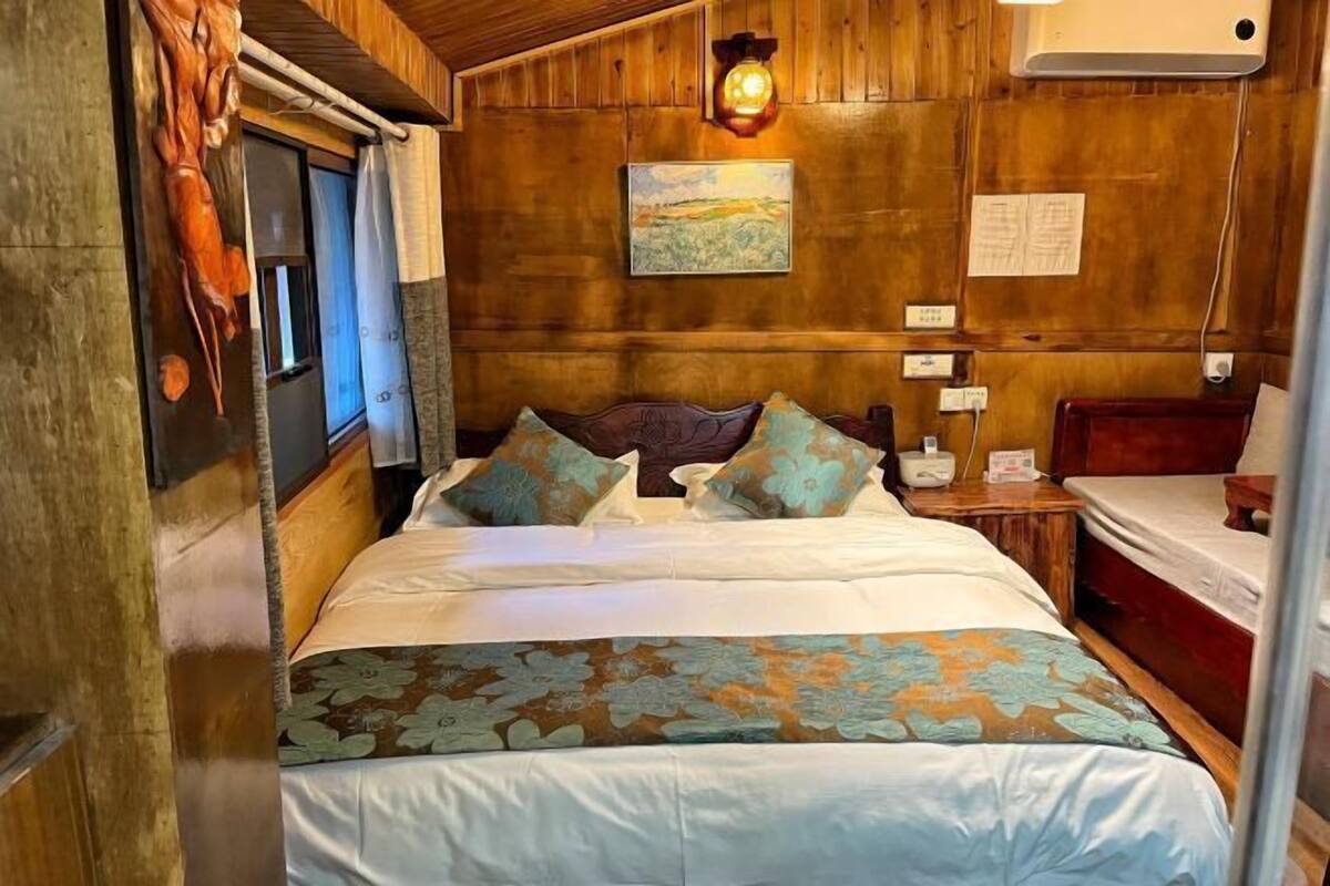 A wooden-paneled room with a bed, a nightstand, and a wall-mounted lamp.