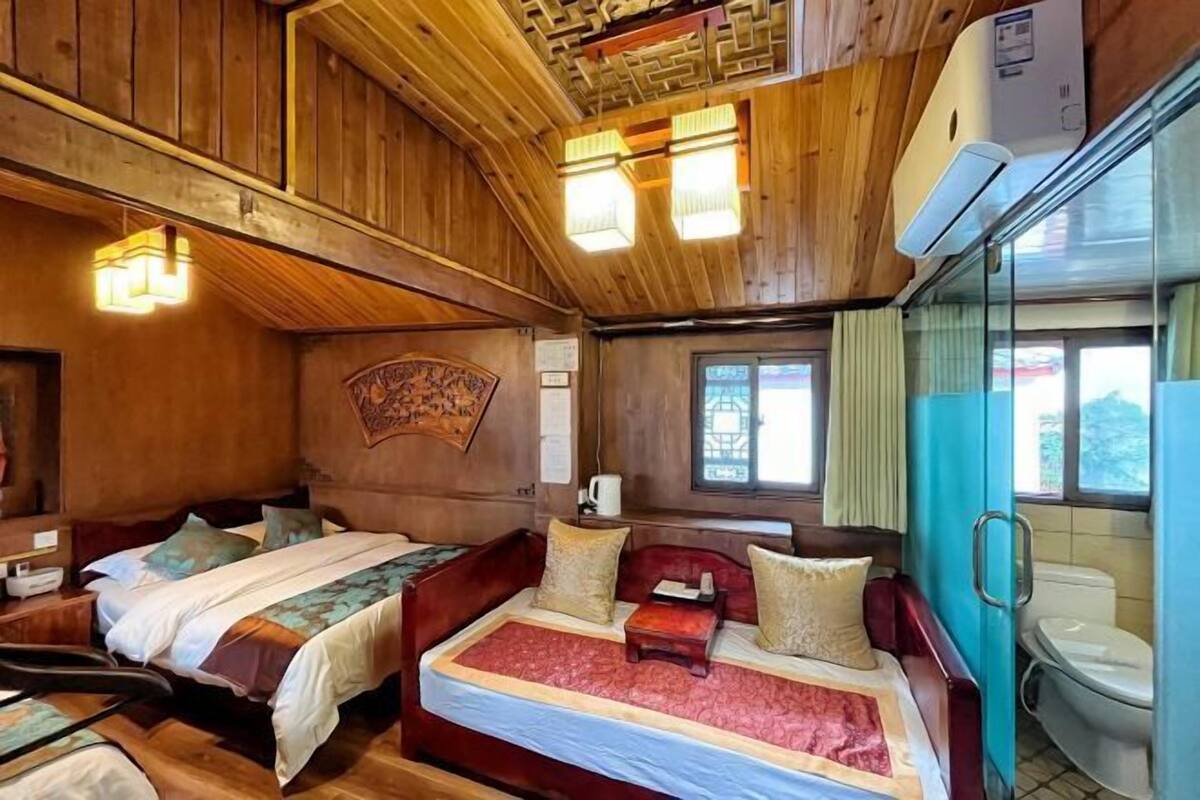 A cabin with two beds, a wooden ceiling, and a bathroom with a toilet and sink.