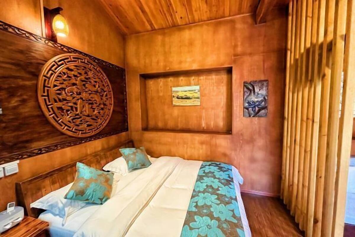 A wooden-themed room with a bed, a decorative wall piece, and a framed picture.