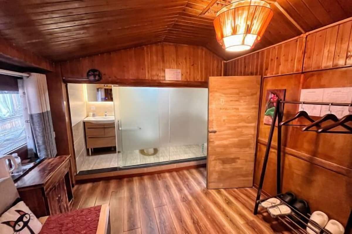 A wooden interior with a glass shower, a wooden bench, and a shoe rack.