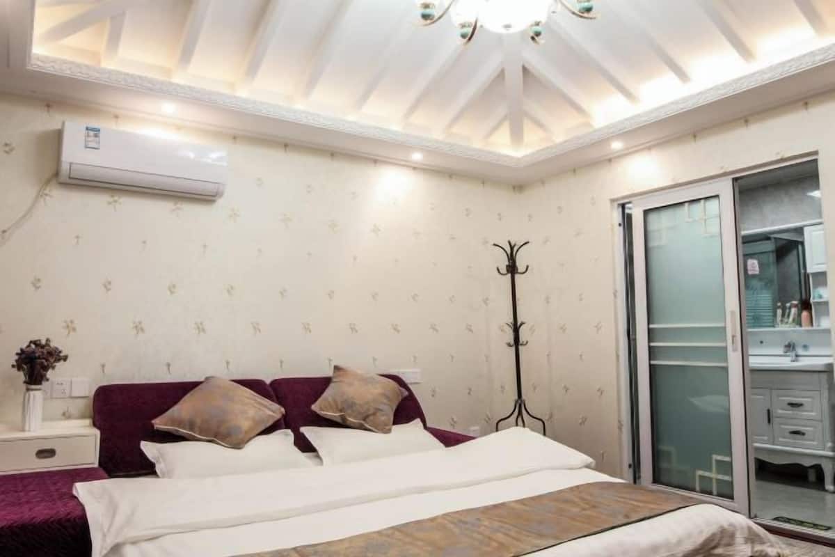 A bedroom with a bed, a nightstand, a mirror, and a wardrobe.