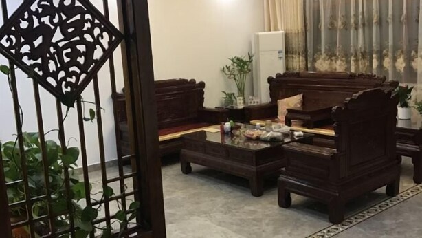 Un salón comedor de estilo tradicional con muebles de madera, una mesa de centro de vidrio y un biombo decorativo.