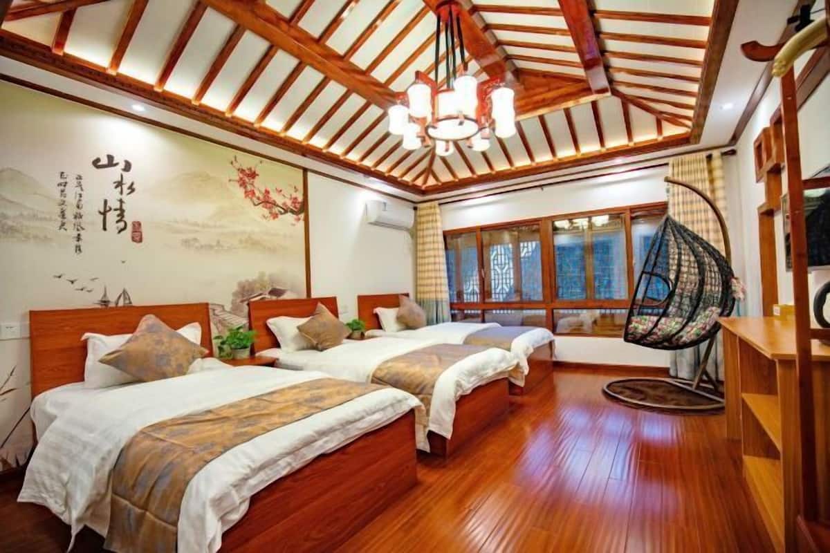 A traditional room with wooden flooring, two beds, a hanging chair, and a large window with curtains.