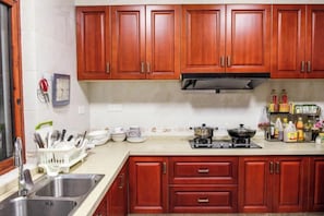 A kitchen with wooden cabinets, a sink, and a stove. - Yunsu Hotel (Kunshan)