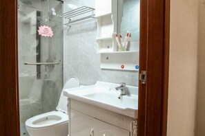 A modern bathroom with a glass shower enclosure, a white sink with a mirror above it, and a toilet.