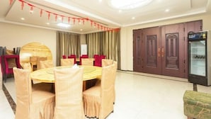 A conference room with a round table, chairs, and a refrigerator. - Yunsu Hotel (Kunshan)
