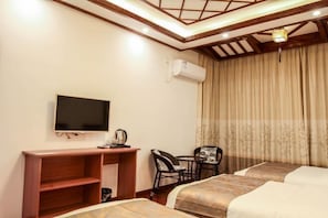 A hotel room with two beds, a TV, a desk with a chair, and a window with curtains.