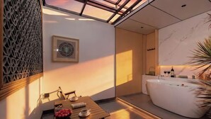 Um banheiro moderno com uma banheira independente, uma mesa de madeira com cadeiras e um objeto decorativo na parede.