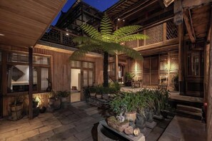 A traditional wooden building with a courtyard, stone flooring, and potted plants.