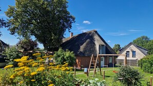 A thatched-roof house with a garden in front. - Vacation apartment Friesenwind (Rantrum)