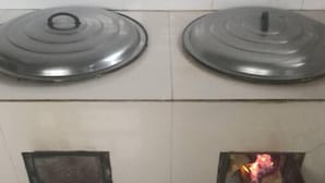 Two stove tops with lids, a tiled floor, and a small fire in a compartment. - Harbin Snow Gu Liang Li Family Hotel (Wuchang)