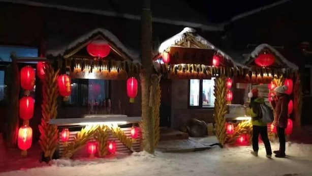 A traditional building with a snow-covered roof and red lanterns. - Harbin Snow Gu Liang Li Family Hotel (Wuchang)