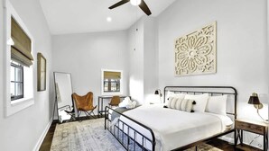 Quarto com cama, escrivaninha, cadeira e ventoinha no teto.