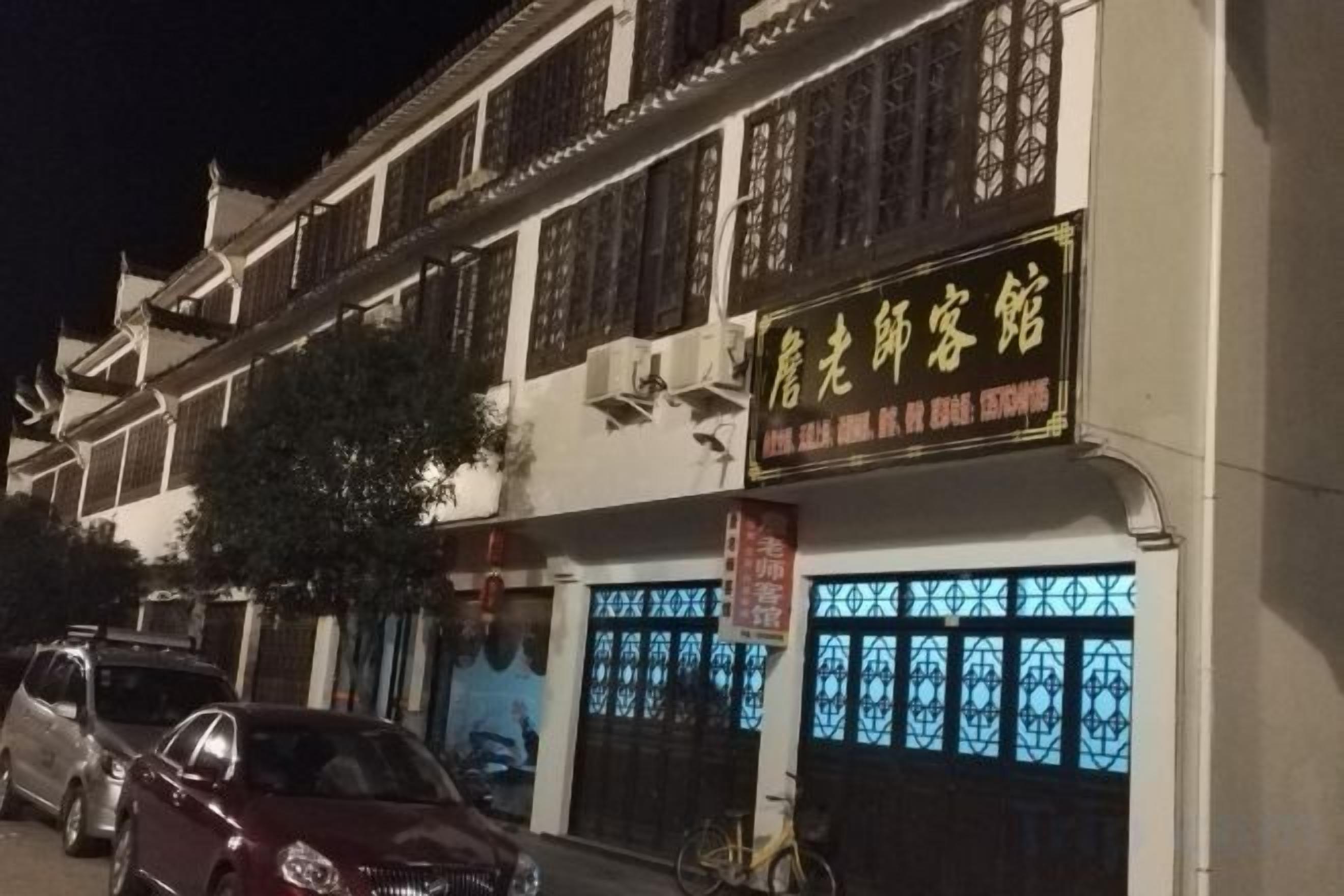 A traditional building with a signboard, a bicycle, and a car parked in front.