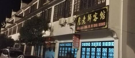 A traditional building with a signboard, a bicycle, and a car parked in front.